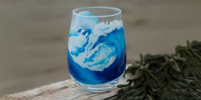 Hand painted Ocean Wave stemless white wine glass on a piece of driftwood with some sea grass