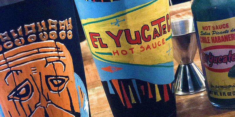 Classic Atomic Age retro barware set with 2 hand-painted cocktail shakers, featuring a tiki face and a bright El Yucateco Hot Sauce logo