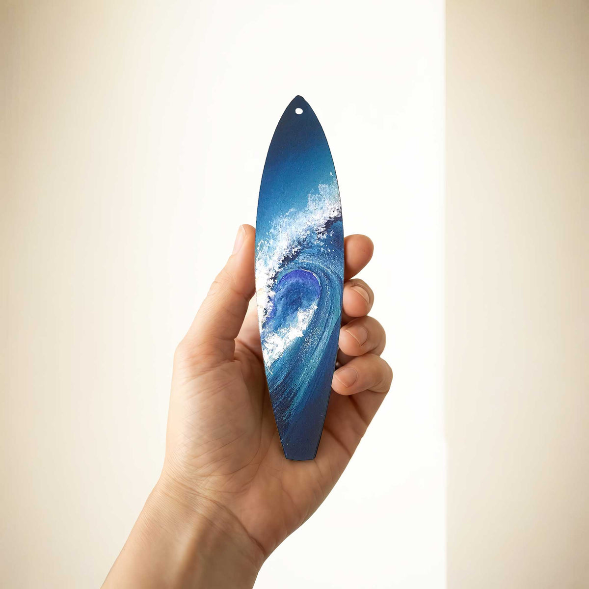 Big Blue surfboard ornament shown in hand for size reference