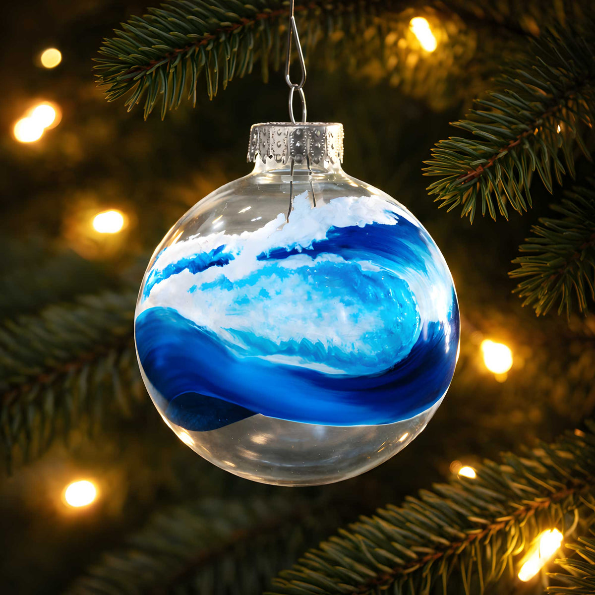 hand-painted bluewater glass wave ornament hanging on lit christmas tree branch