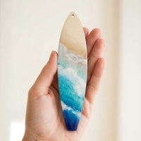 Castaway surfboard holiday ornament shown in hand for size reference