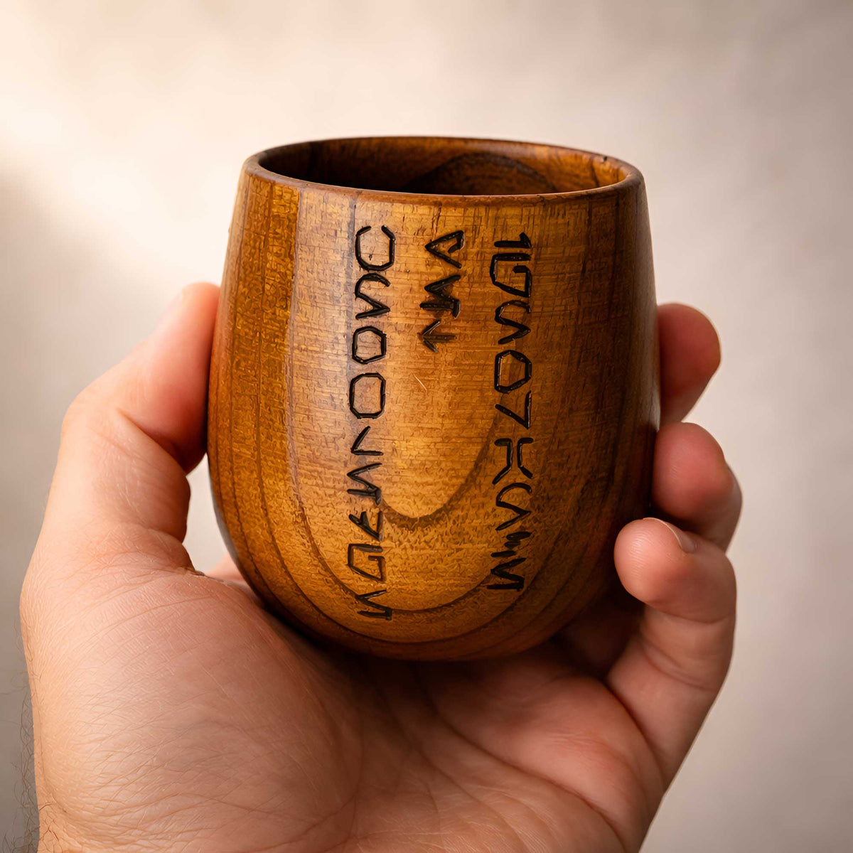 Hand holding a Kar’tam Jedi Code wooden cup to show size, weight, and natural wood finish