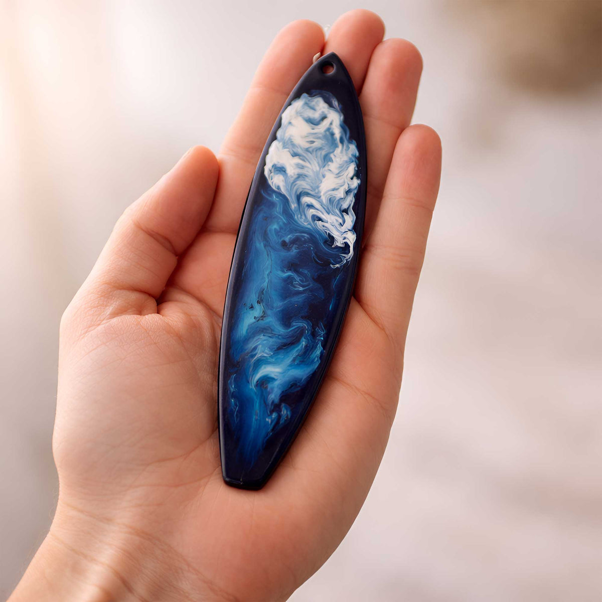 Kauai surfboard ornament shown in hand for size reference