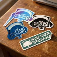 Kyberpunks stickers and enamel pin close up on wood surface