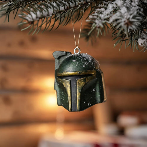 Boba Fett–inspired Mandalorian helmet ornament hanging on a Christmas tree with snow and warm lights.