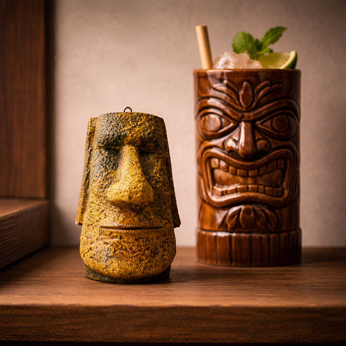 handmade gold tiki moai ornament with aged metallic stone texture standing on a bar next to a tiki mug