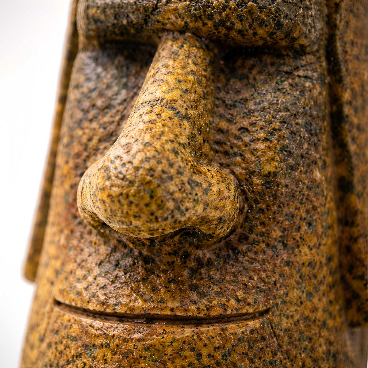 closeup view of gold merry moai tiki ornament showing rough stone texture