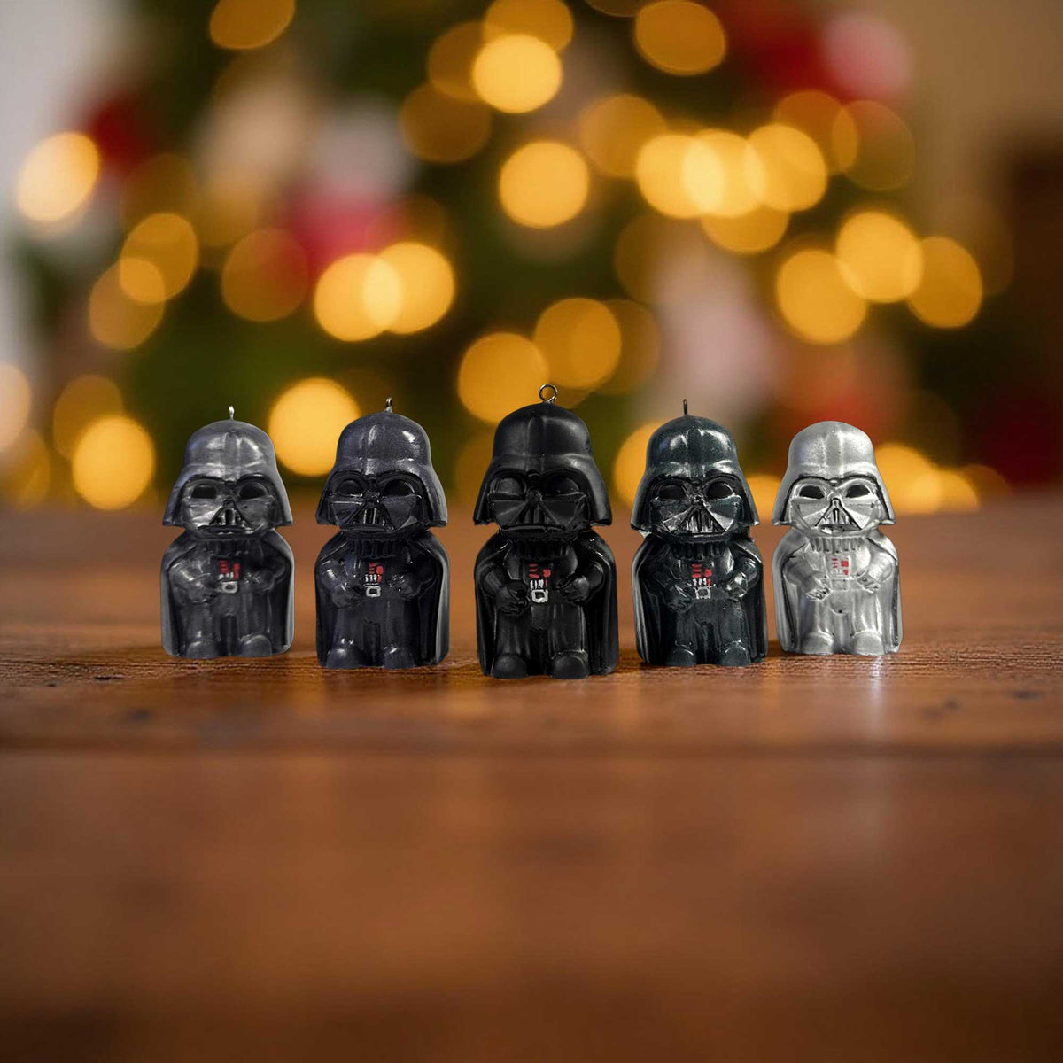 Mini Darth Vader ornaments in multiple colors displayed on a wooden table with holiday lights in the background.