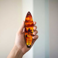 santa’s getaway surfboard ornament shown in hand for size reference