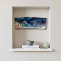 starfish shores resin art hanging in a nook above coastal decor