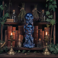 Three Wise Skulls figurine styled on a witchy apothecary shelf with books candles and botanical decor