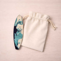 by the sea surfboard ornament beside an unbranded canvas gift bag