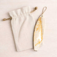 White Gold surfboard ornament resting beside canvas gift bag