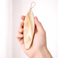 White Gold surfboard ornament held in hand for scale