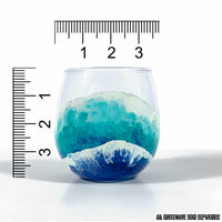 Single red wine glass of a beach barware set with hand-painted waves by 5th & Rugged. Shown with scale for size reference.