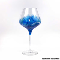 Custom glassware with hand-painted ocean waves washing up a red wine glass in blue and white.