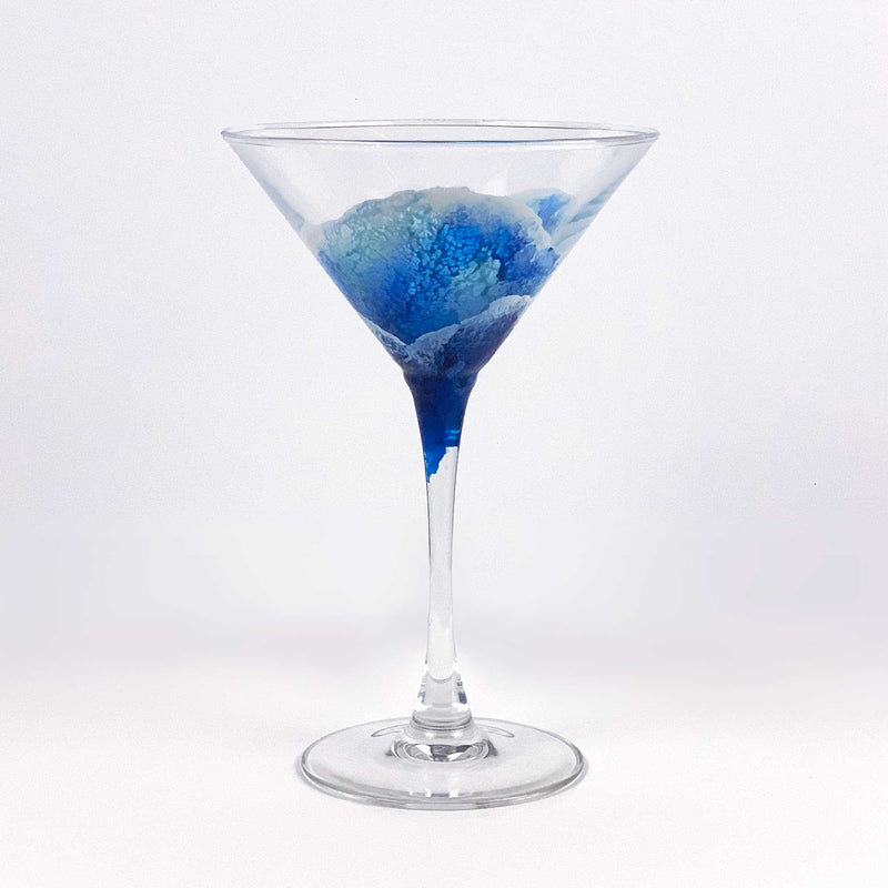 Retro cocktail glass with abstract blue surfing waves painted around the glass, using a contemporary, highly textured style.