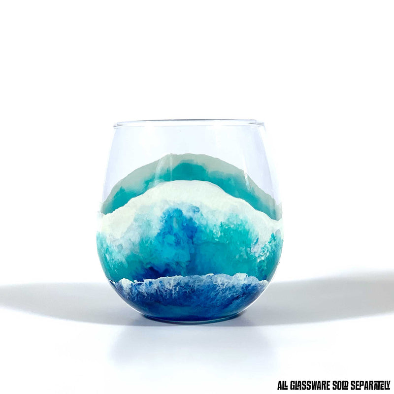Custom glassware with hand-painted ocean waves washing up a stemless red wine glass in blue, white, and turquoise.