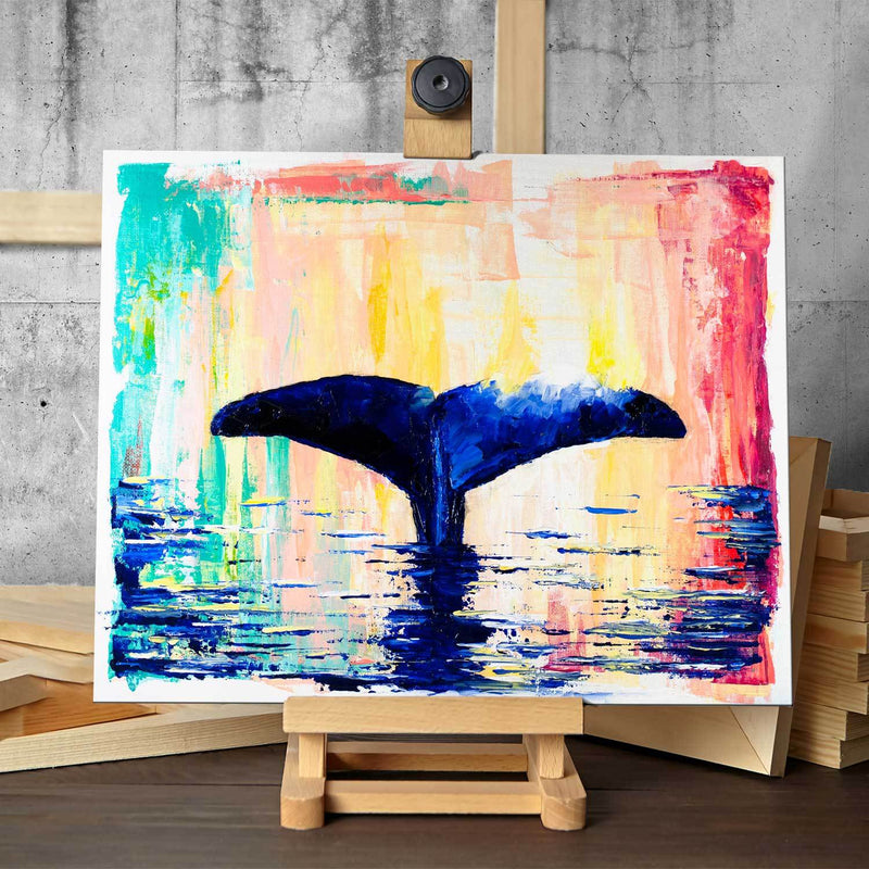 Original painting of deep blue whale tail against abstract rainbow background on easel