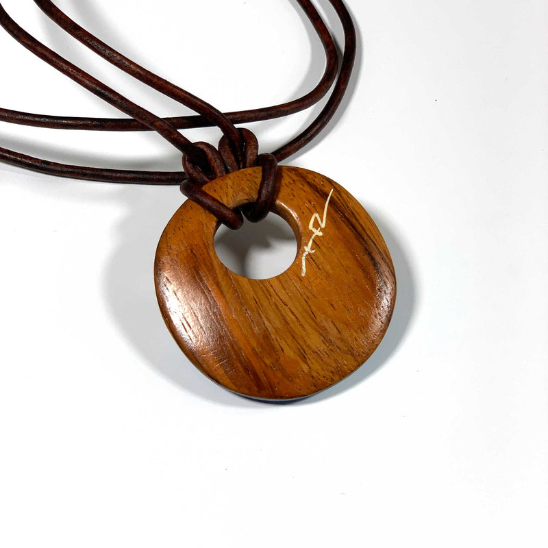 Round wood pendant necklace made of eco-friendly wood signed by the artist on a white background
