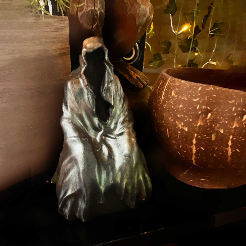 A Hallowen Decor figurine of the Grim Reaper in color shifting green robes against a halloween decor background.