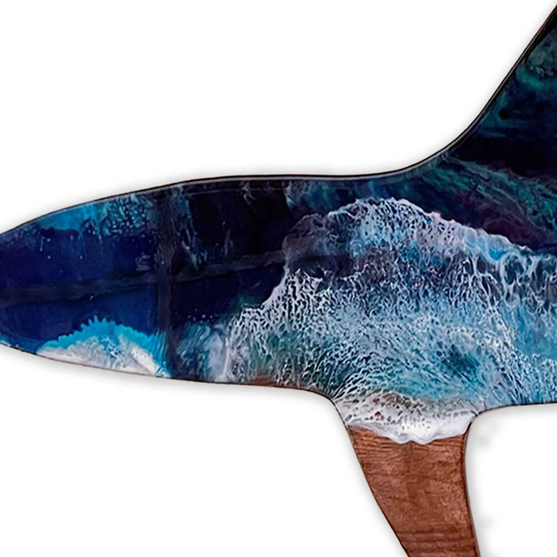 A closeup of a hand painted wooden shark with art resin like ocean waves painted on top
