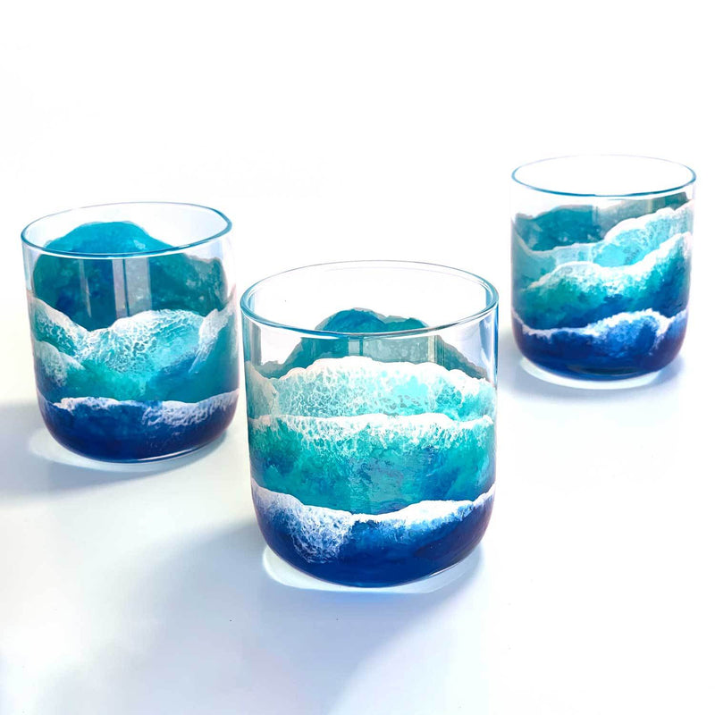 Trio of custom cocktail glasses with painted beach waves on clear glass ocean barware.