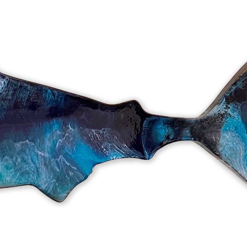 A closeup of a hand painted wooden shark with art resin like ocean waves painted on top