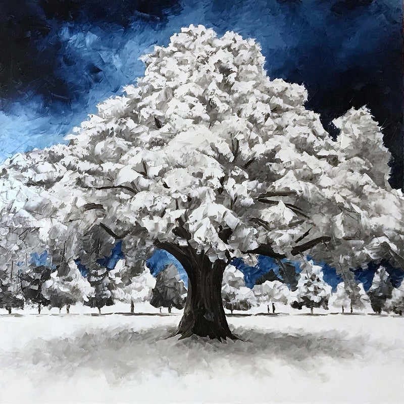 Nature wall art of snow covered winter tree against deep blue sky. Beautiful blue and white winter decor idea.